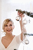 Young woman decorating Christmas tree