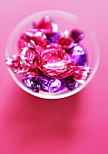 Sweets in pink and purple wrappers in a small bowl
