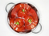 Three red peppers in a colander