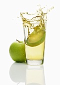 Wedge of apple falling into a glass of apple juice