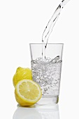 Pouring water into a glass & lemons