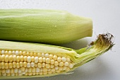 Two corn cobs with husks and silk