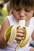 Small child biting into a banana