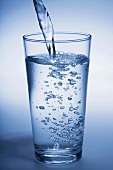 Ein Glas Mineralwasser eingiessen