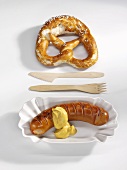 Red sausage with mustard and pretzel