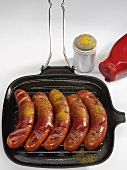 Five currywurst (sausages with ketchup & curry powder)in grill pan