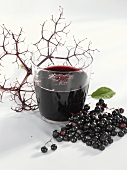A glass of elderberry & apple juice & fresh elderberries