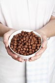 Hands holding a bowl of chocolate flavoured puffed rice