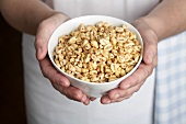 Hands holding a bowl of puffed wheat breakfast cereal