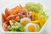 Mixed salad with ham and egg in plastic container