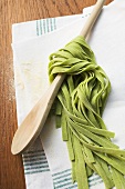 Green ribbon pasta wrapped around a wooden spoon