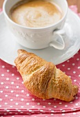 A croissant with a cup of cappuccino