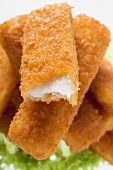 Fish finger with a bite taken on a heap of fish fingers