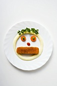 Face formed from fish finger, mashed potato and vegetables
