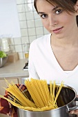 Woman holding a pan of uncooked spaghetti