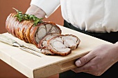 Rolled saddle of suckling pig on a wooden board