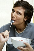 Young man licking quark from spoon