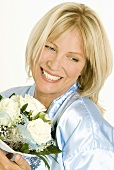 Smiling woman holding bouquet of white roses in her hands