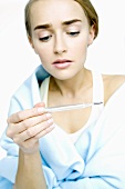 Woman with cold reading clinical thermometer