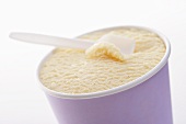 Vanilla ice cream in cardboard tub with plastic spoon
