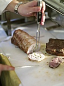 Slicing a rolled roast with herb stuffing