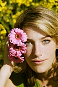Young woman putting pink gerberas behind her ear