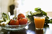 A glass of juice beside a dish of vegetables