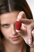 Young woman holding a raspberry