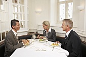 Woman between two men at a business meal