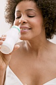 Junge Frau trinkt Milchdrink aus einer Plastikflasche