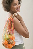 Young woman with a string bag full of fruit