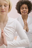 Zwei junge Frauen mit geschlossenen Augen beim Meditieren