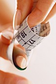 Tape measure coiled between fingers (close-up)