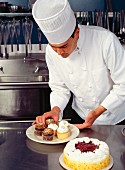 A chef in a kitchen preparing cupcakes and cakes