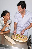 Paar beim Pizza belegen in der Küche