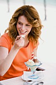 Woman eating ice-cream sundae in cafe