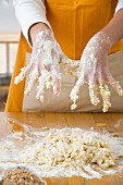 Woman with dough on hands kneading dough