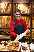 Shop assistant in bakery with pastries and baguettes