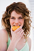Woman biting into half an orange