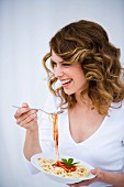 Young woman eating spaghetti with fork, portrait