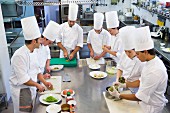 A head chef with trainee chefs in a commercial kitchen