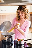 Woman at cooker cooking spaghetti in boiling water