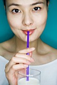 A woman drinking milk through a straw