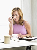 Woman drinking coffee sitting at her desk