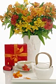 Vase of flowers, gift, cup of tea and teapot