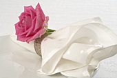 Fabric napkin with pink rose on white plate