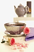 Tea in silver cup & saucer with roses, teapot, aroma lamp