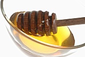 Honey and honey dipper in glass (close-up)