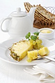 Pineapple and grapes on plate, teapot, butter, crispbread