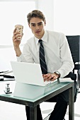 Young man drinking coffee out of paper cup in office